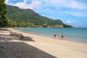 people running along an empty beach on Mahe in the morning, Seychelles