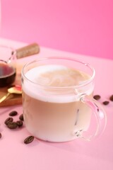 Cup of fresh coffee and beans on pink table