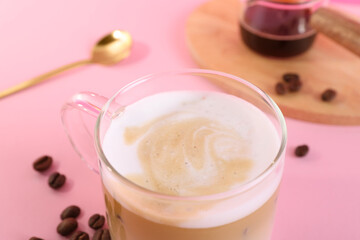 Cup of fresh coffee and beans on pink table, closeup