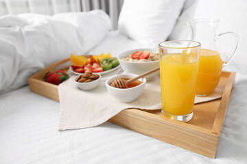 Wooden tray with tasty breakfast on bed at home