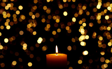 Candle burns Isolated On Black background with Christmas Lights Defocused Bokeh.