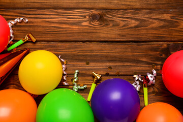 Balloons, noisemakers and confetti on wooden background