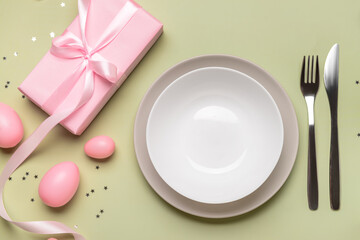 Beautiful Easter table setting with gifts and eggs on green background