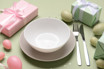 Beautiful Easter table setting with gifts and eggs on green background