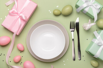 Beautiful Easter table setting with gifts and eggs on green background