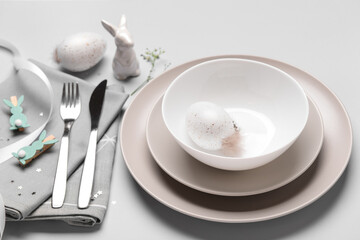 Modern Easter table setting with eggs and bunnies on white background