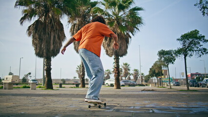 Cool skater balancing skateboard performing skating on street. Guy training