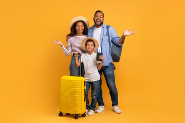 Portrait of excited black family of three with suitcase and travel tickets