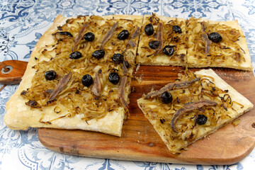 Pissaladière coupé en part, en gros plan, sur une table