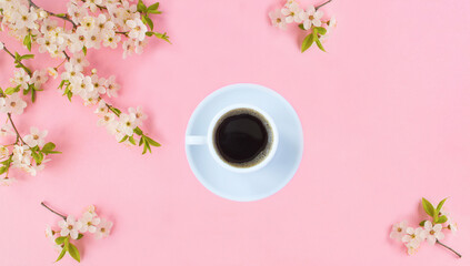 Coffee cup and white flowering tree branches on the pink background. Top view. Copy space.