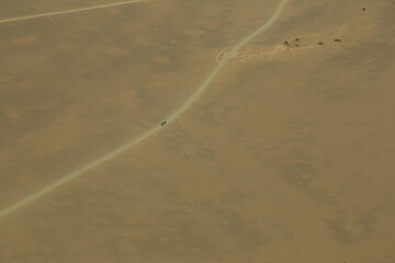 aerial photography of a off-road vehicle on a gravel road in namib desert
