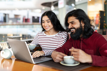 Indian couple using laptop at cozy cafe
