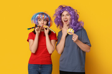 Young friends in funny disguise with paper smile and whistles on yellow background. April fool's...