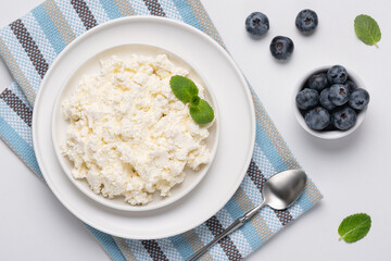 Cottage cheese with blueberry and mint on a white table. Cottage cheese in a bowl. Top view. Dairy products