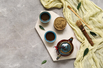 Composition with ceramic teapot, cups of tea, chashaku and chasen on grey background