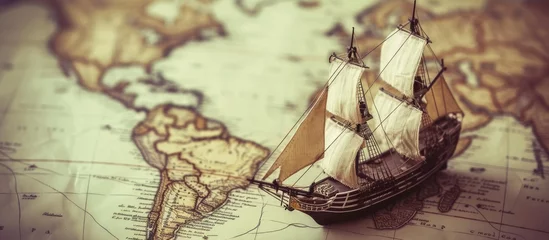 Foto op Canvas A model ship rests on a detailed map of the world, showcasing timeless charm and the spirit of exploration. The combination of the old ship and map invites viewers to appreciate the magnificence of © AkuAku