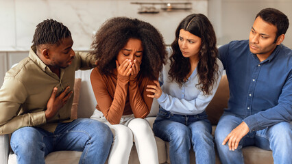 Diverse friends providing support to unhappy crying black lady indoor