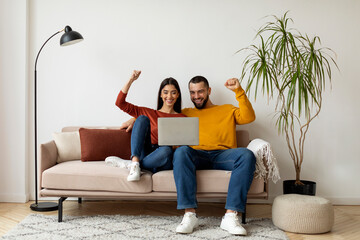 Happy Excited Young Couple Celebrating Success With Laptop At Home