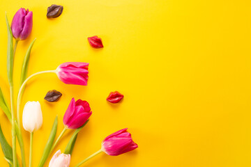 Yellow tulips and chocolate lips on a yellow background, top view, international woman's day,...