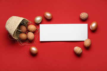 Fallen basket with Easter eggs and blank card on red background. Top view