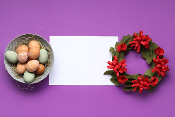 Naklejka na ściany i meble Easter eggs, felt wreath and blank greeting card on purple background. Top view