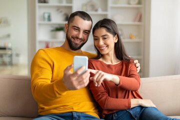 Shopping App. Happy Young Couple Using Smartphone At Home Together