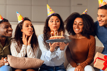 multicultural friends gathering in living room to celebrate birthday