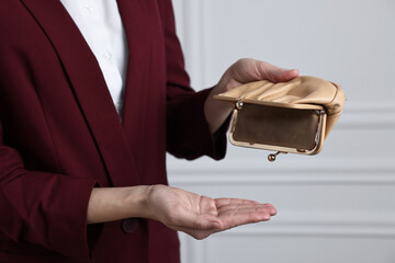 Woman with empty wallet near white wall, closeup