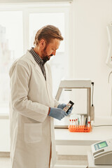 Scientist in uniform holding test tubes at laboratory. Medicine and research in chemistry