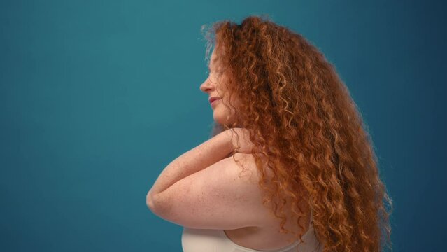 Young pretty redhead plus size or plump woman celebrating her natural body. Positive beautiful female model in white underwear against blue background. Lifestyle portrait with minimal makeup