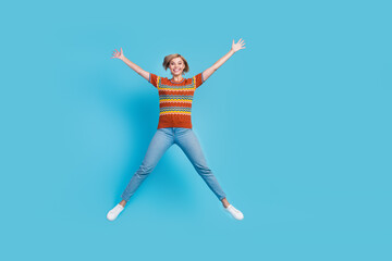 Fototapeta na wymiar Full size photo of good mood positive woman dressed knit t-shirt denim trousers flying like star isolated on blue color background