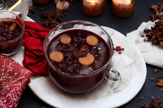 Mulled wine with chocolate and spices on a wooden background.