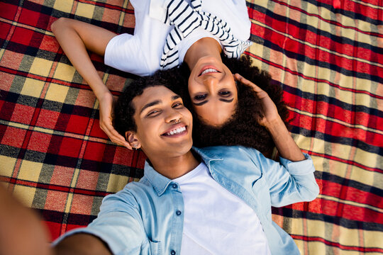 High angle view portrait of two peaceful idyllic people laying blanket cuddle take selfie record video