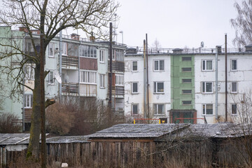 Fototapeta na wymiar old damaged multiapartment building in Latvia countryside. Aged walls and window frames, metal chimneys, satellite dishes, soviet leftovers. Shelter for poor people