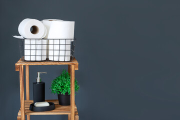 Basket with toilet paper rolls and bath supplies on wooden shelving unit.