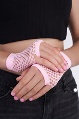 Cropped shot of a woman wearing a black T-shirt, jeans and pink mesh mittens. The Girl is posing on a the white background.