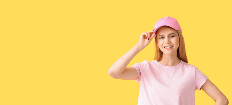 Beautiful young woman in stylish baseball cap on yellow background with space for text