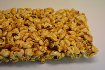 Breakfast, unusual sweets, a bar of nuts, puffed rice in caramel is located on a white background.