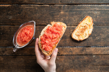 a hand holding freshly toasted bread with natural tomato and extra virgin olive oil in the morning...