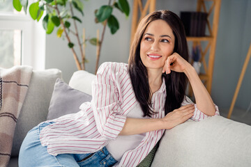 Photo of lovely positive person sit couch toothy smile imagine fantasize enjoy free time chill...