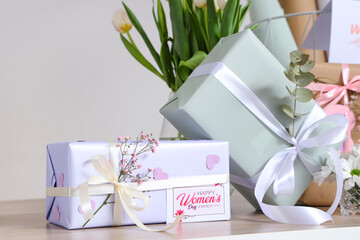 Beautiful gifts and tulip flowers on wooden table against grey background. International Women's Day