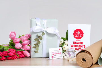 Gift box, beautiful tulip flowers and greeting card for International Women's Day on wooden table against light background