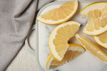 Board with tasty pomelo slices on white background