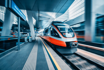 Orange high speed train in motion at modern railway station in Vienna. Fast intercity passenger...