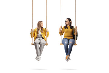 Female friends sitting on wooden swings and looking at each other