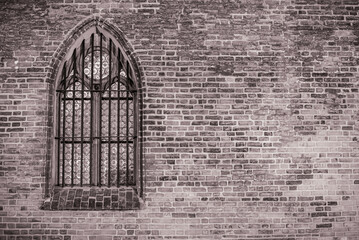 Okno z witrażem po lewej osadzone w ceglanej ścianie w czerni i bieli