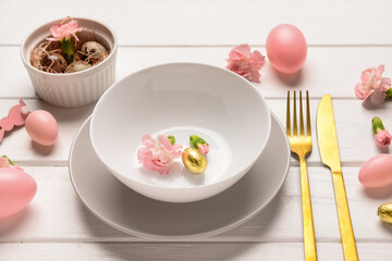 Modern Easter decorated table setting with flowers and eggs on white wooden background