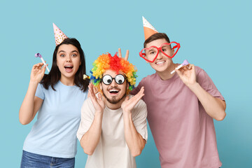 Young friends in funny disguise with party whistles on blue background. April fool's day celebration