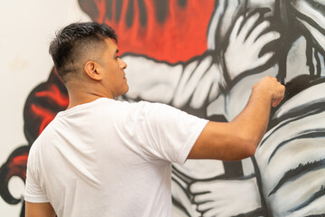 Young latin man artist painting public mural