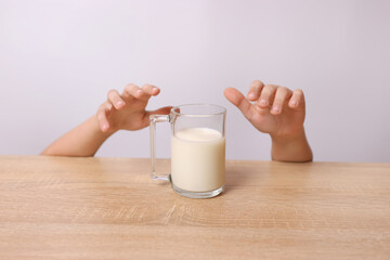 From under the table you can see the child's hands trying to pick up a glass of milk.